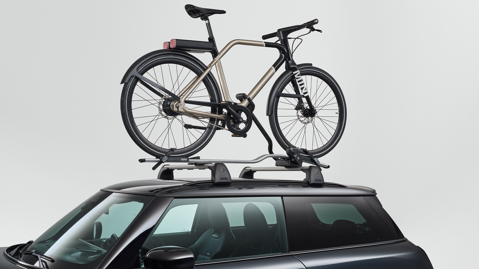 MINI Aceman in Indigo Sunset Blue equipped with MINI Roof Cycle Carrier, carrying two mountain bikes, three quarter rear view. 